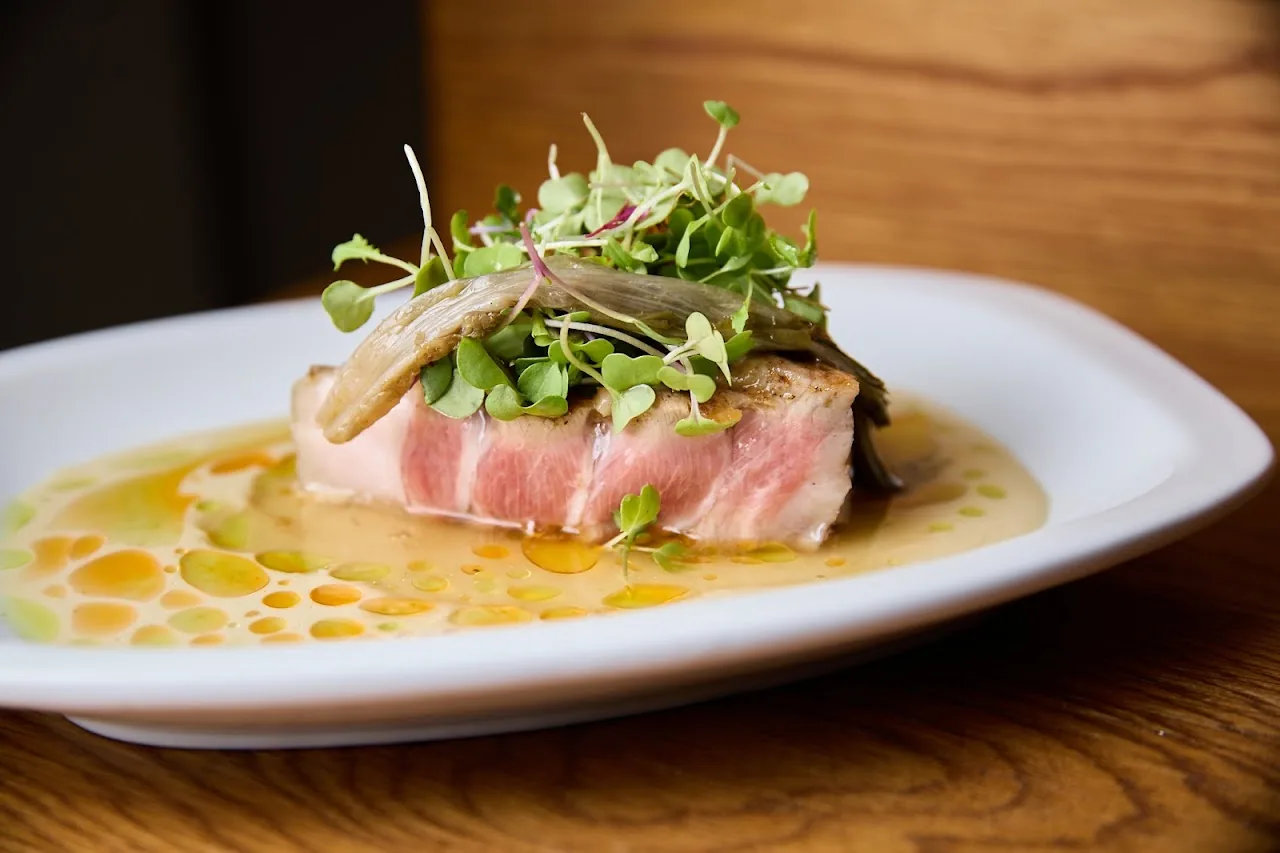 A seared piece of tuna over greens in a light broth