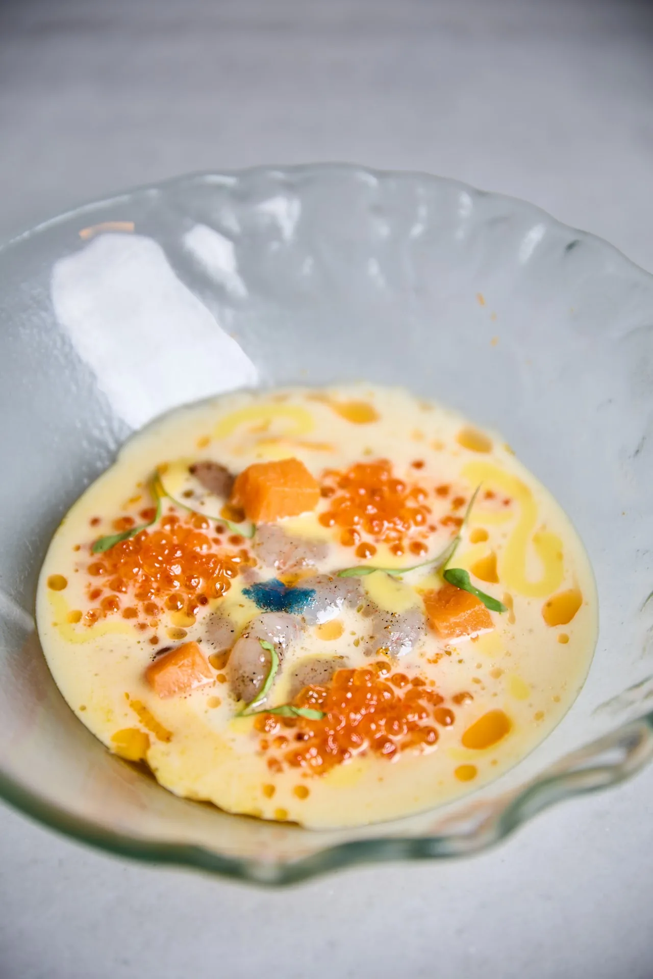 A creamy soup topped with orange fish roe and diced vegetables