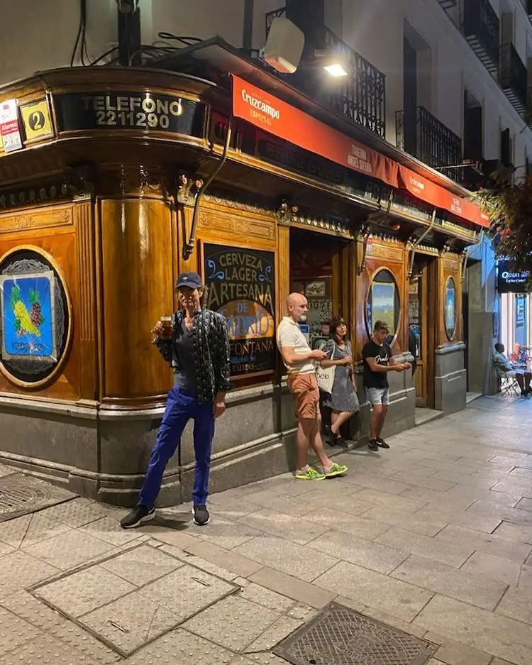 The tiled and wood-paneled corner exterior of Taberna de Angel Sierra at night, with people standing outside