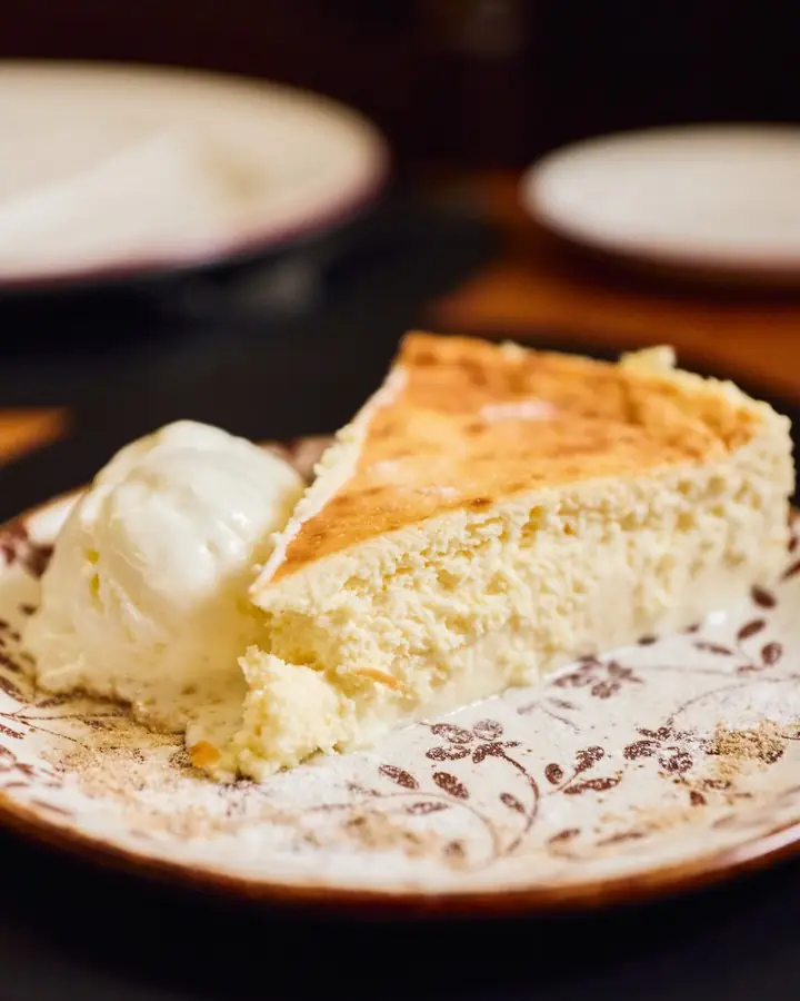 Cheesecake slice with a scoop of ice cream on a decorative plate