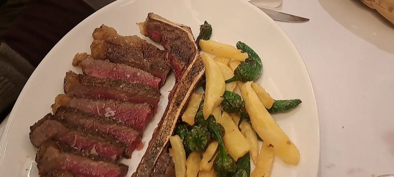 Sliced grilled steak with green beans on a white plate