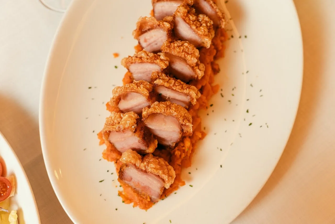 Sliced pork belly with a red sauce fanned out on a plate