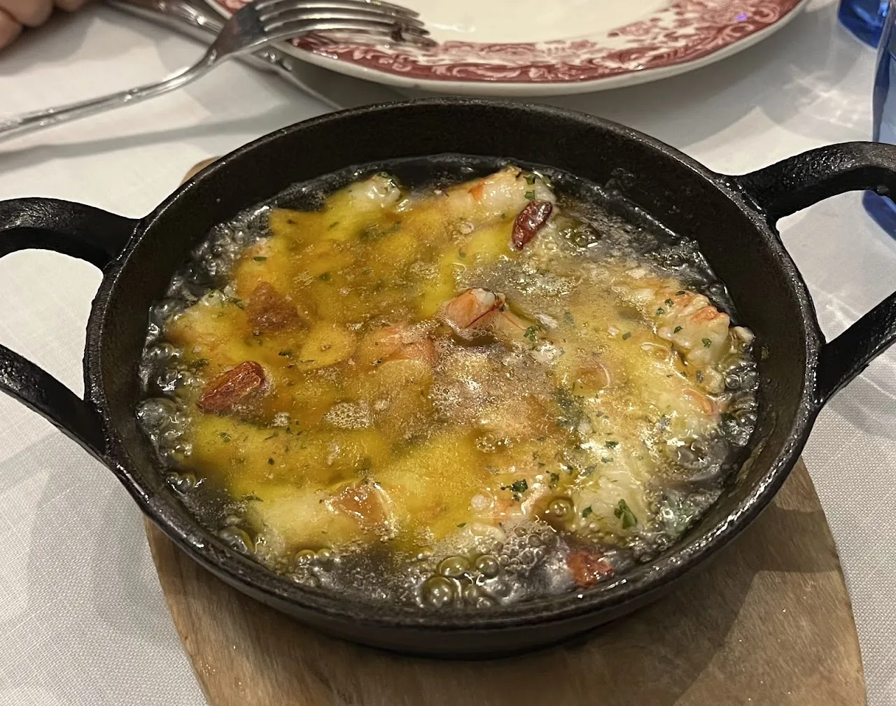 A cast iron dish of sizzling garlic shrimp