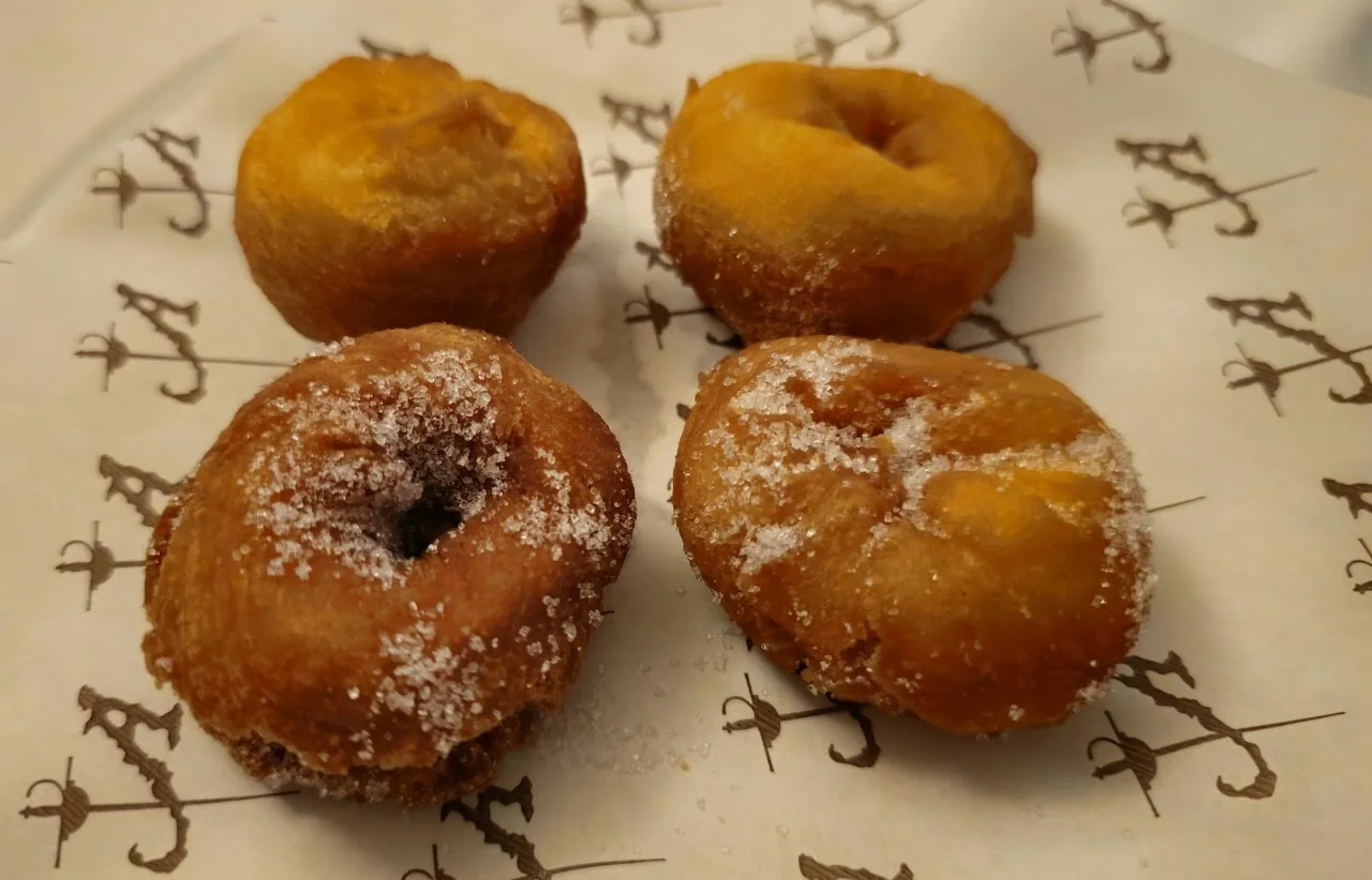 Four sugared fried dough balls on a plate