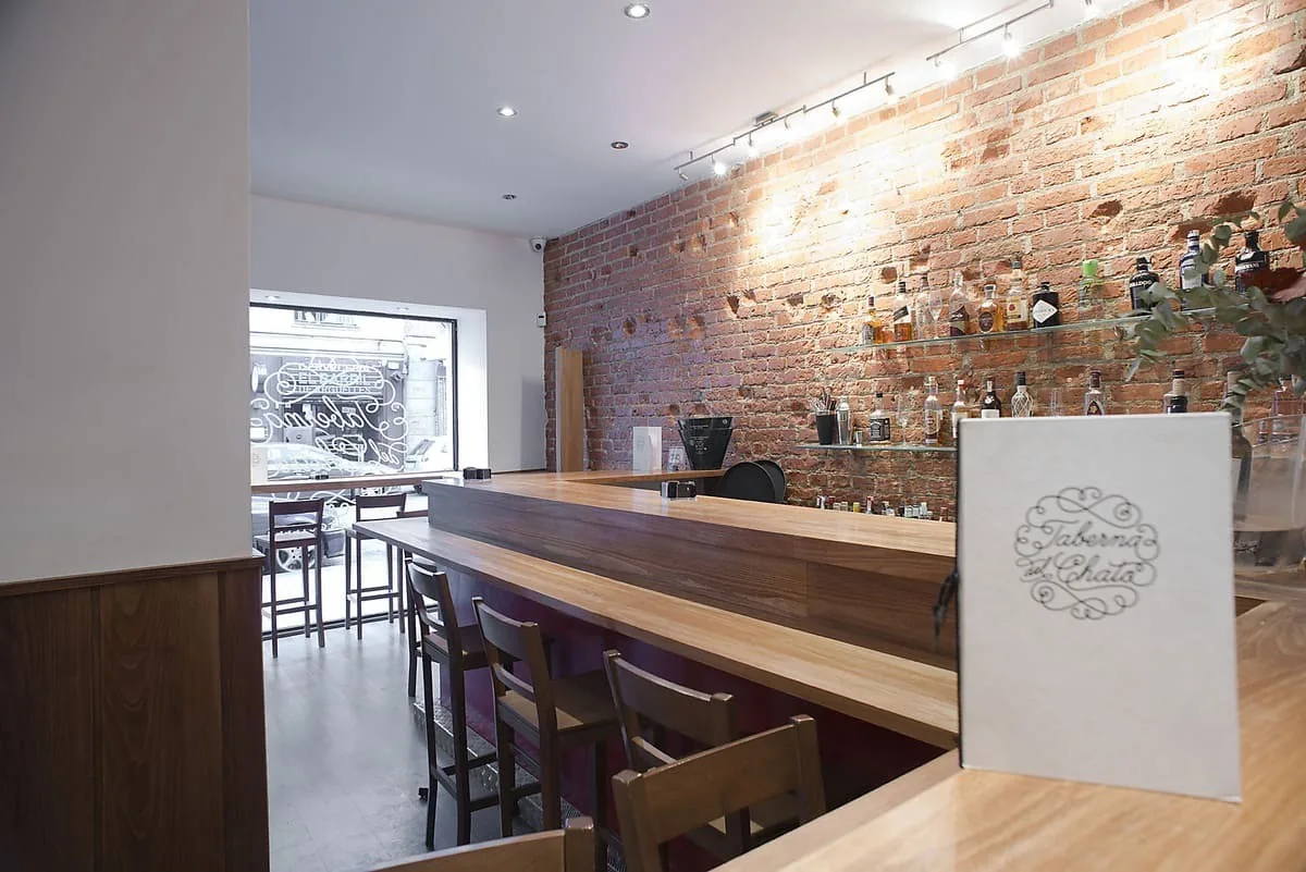 A wooden bar counter along a brick wall in a bright room