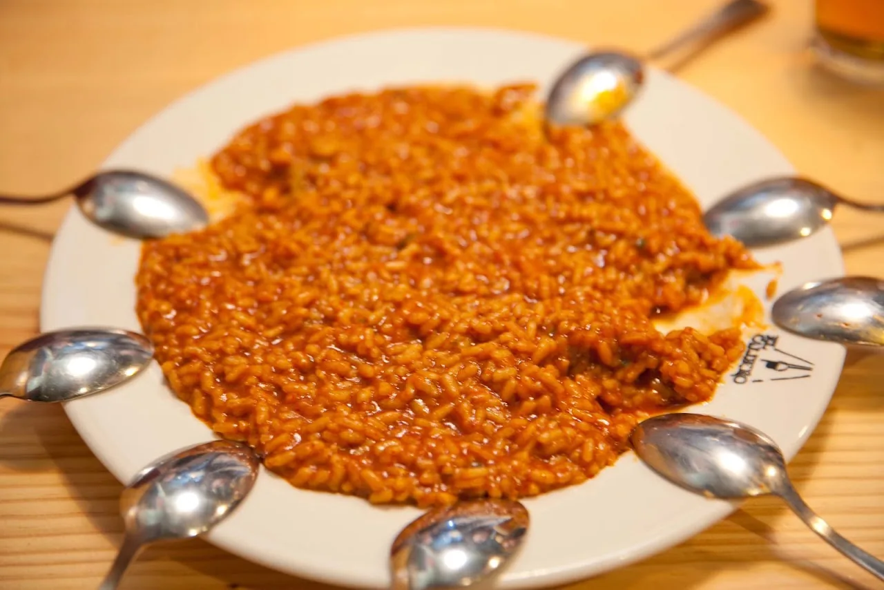 A plate of orange-hued rice dish surrounded by spoons