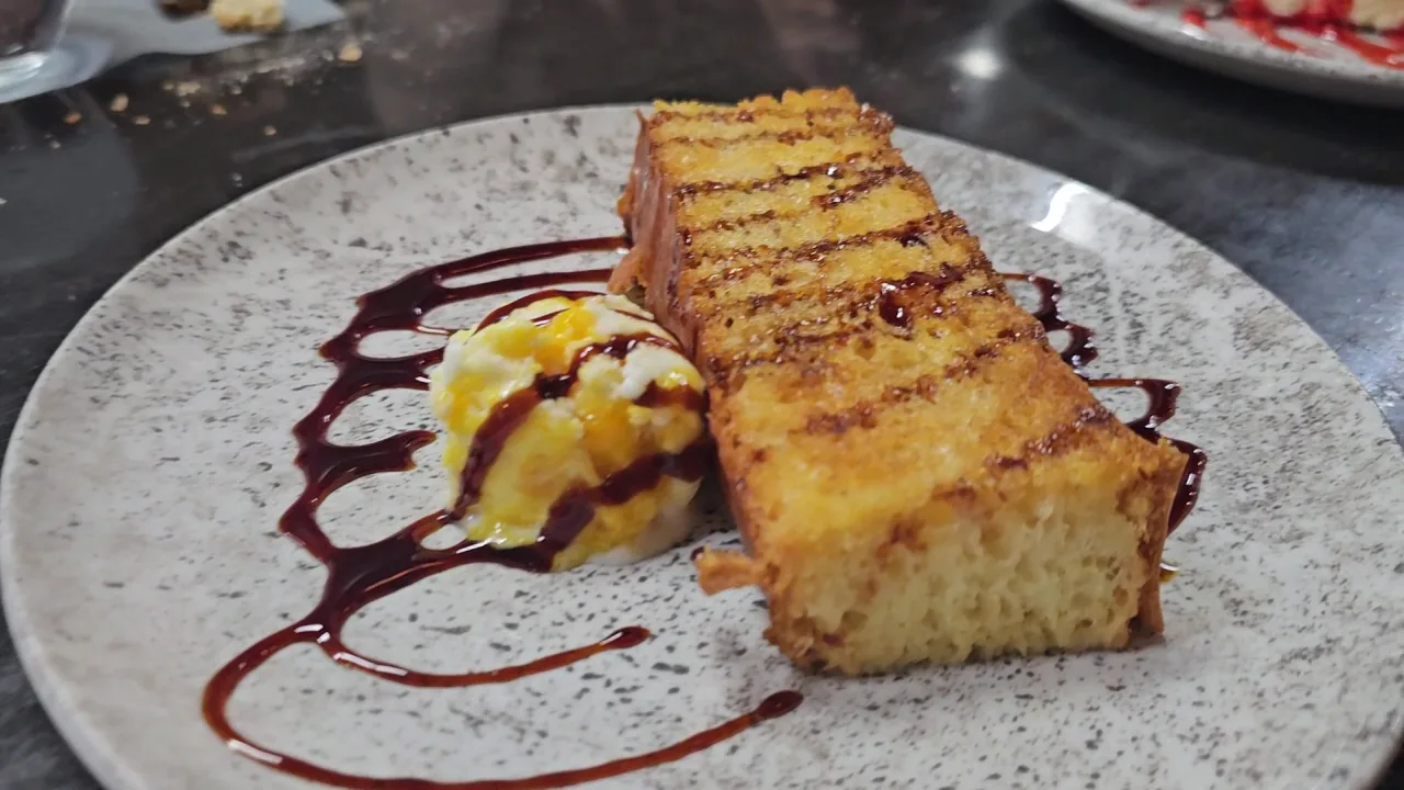 A grilled dessert cake square with a berry sauce drizzle