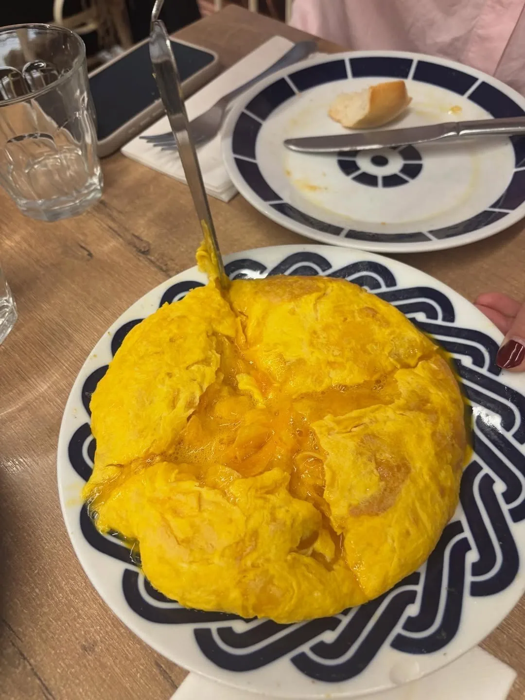 A round bright yellow potato omelette on a blue and white patterned plate