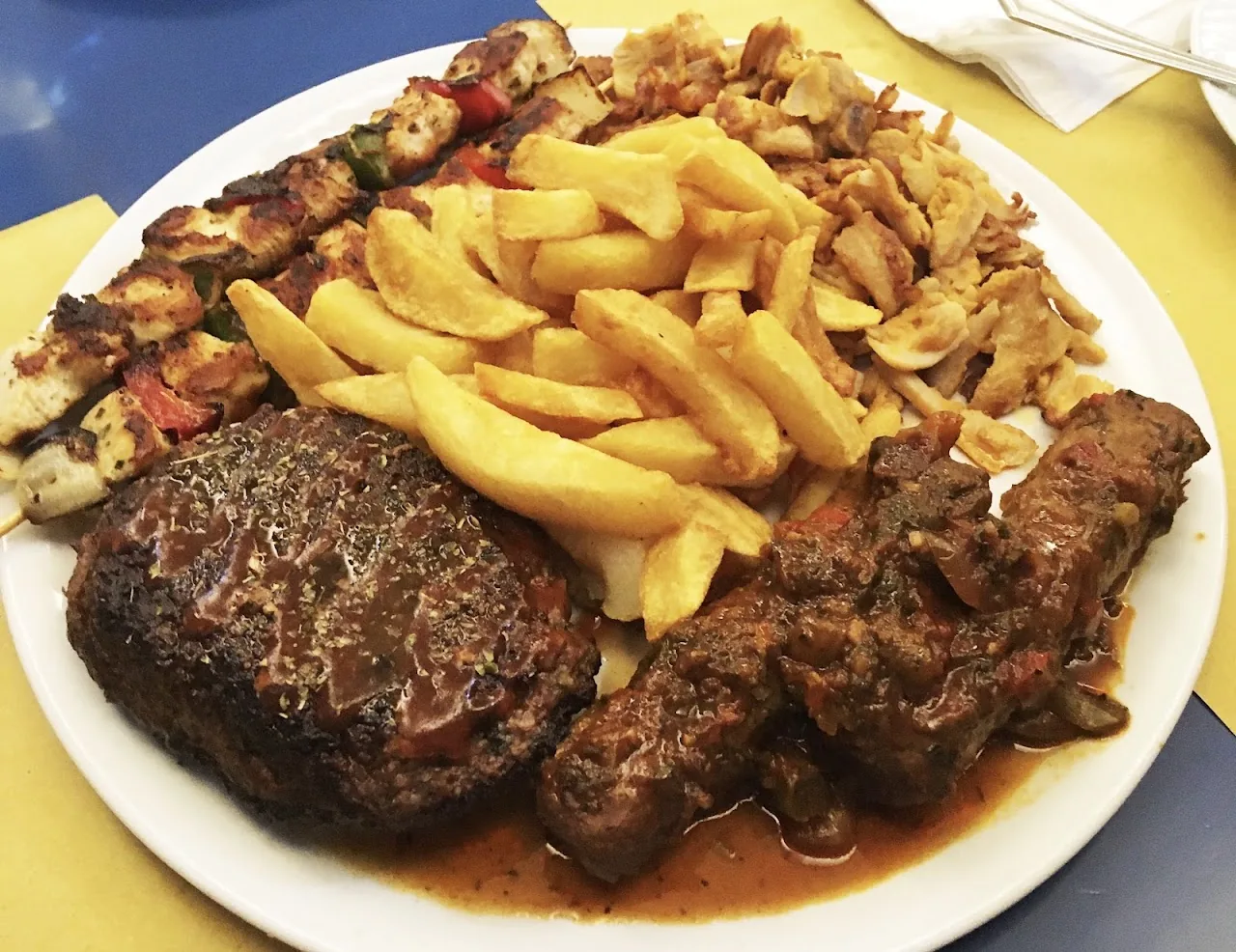 A platter of grilled meat skewers with french fries