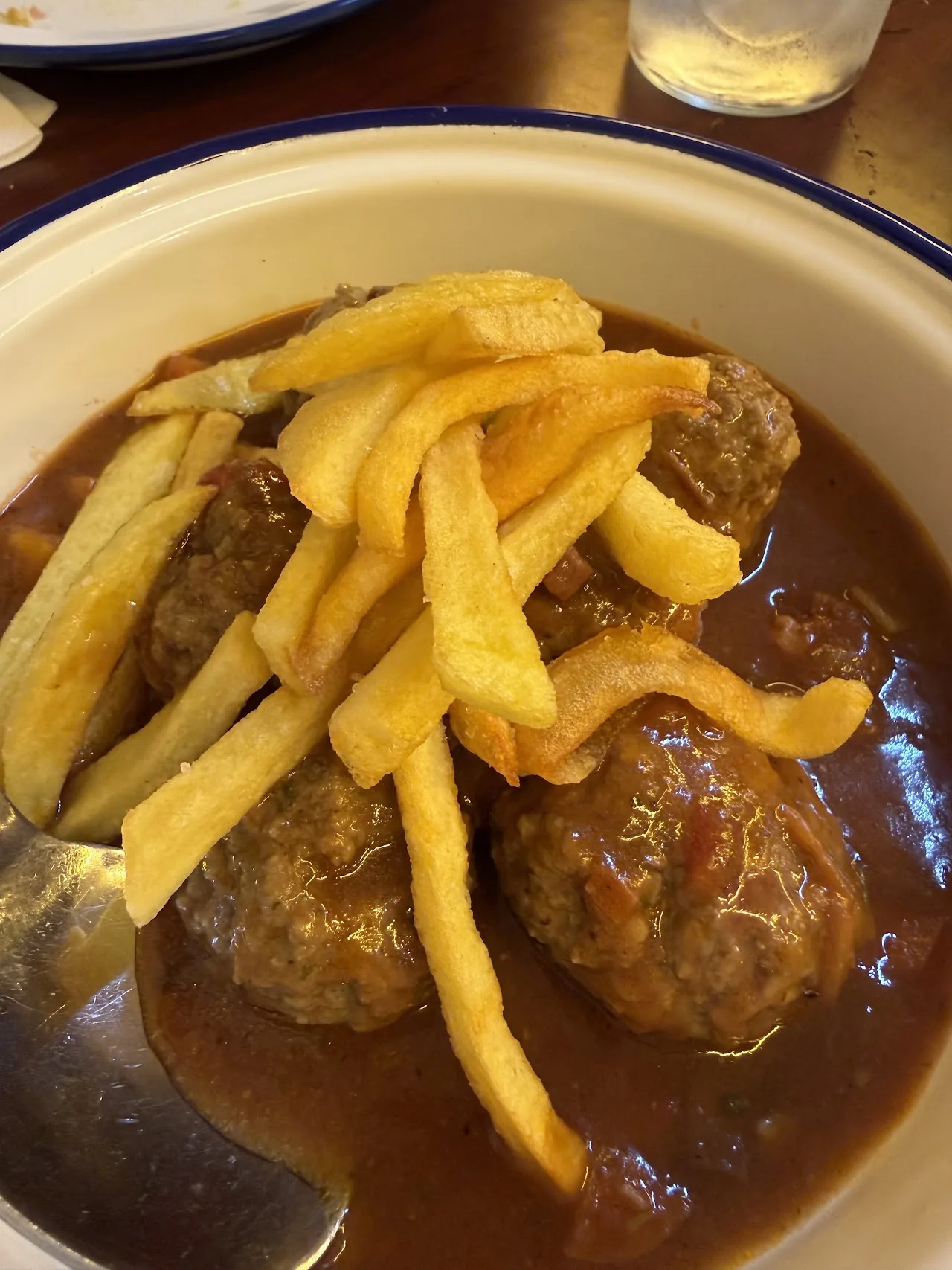 Meatballs in gravy sauce with a side of fried potatoes