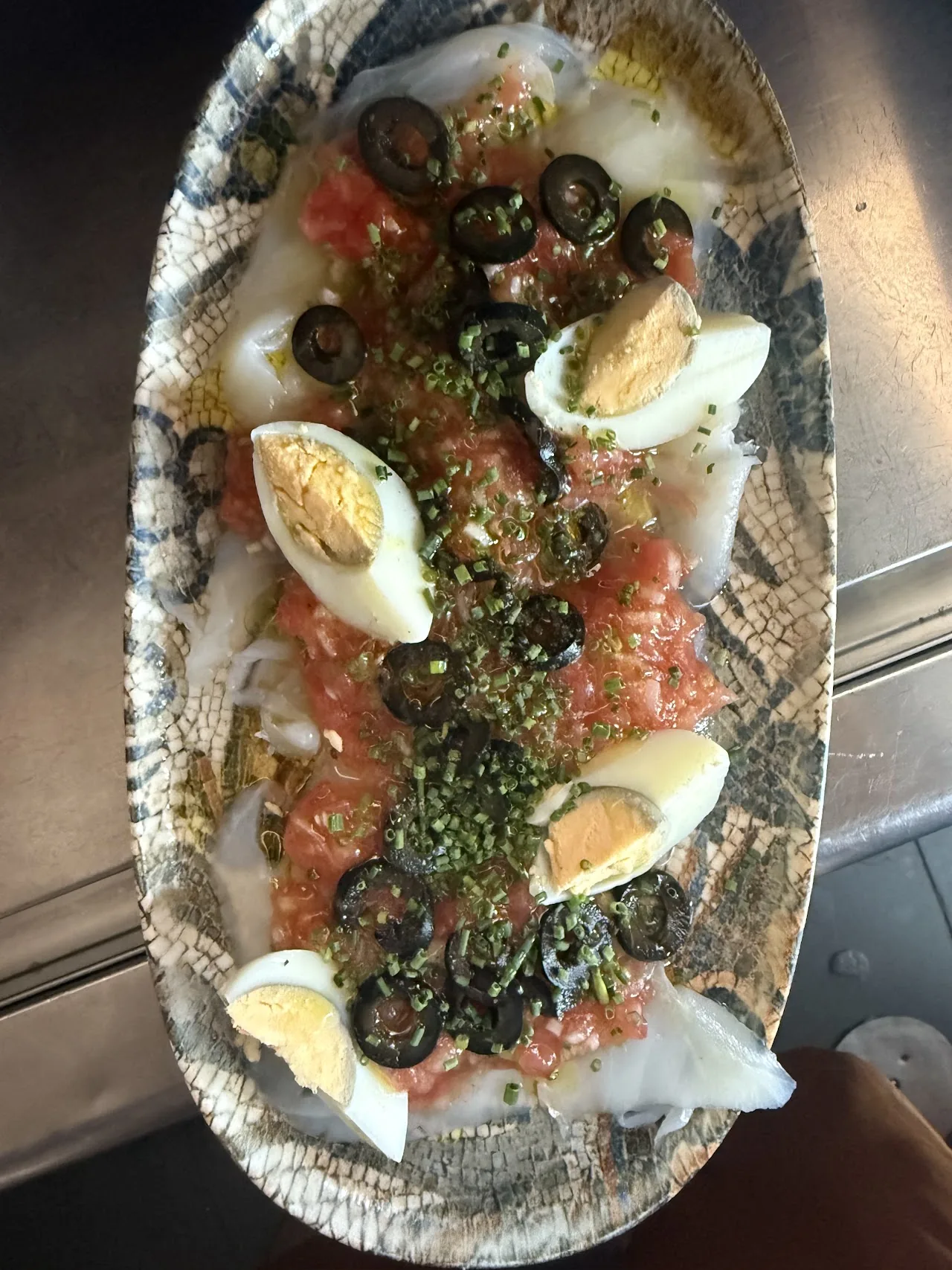 Sliced hard-boiled eggs with tomato, olives and herbs