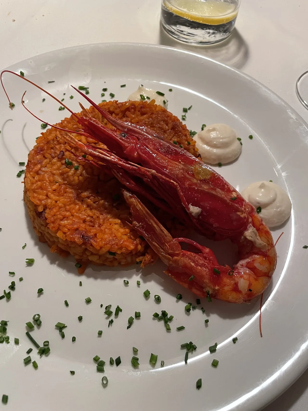 A breaded seafood cake topped with a grilled prawn on a plate