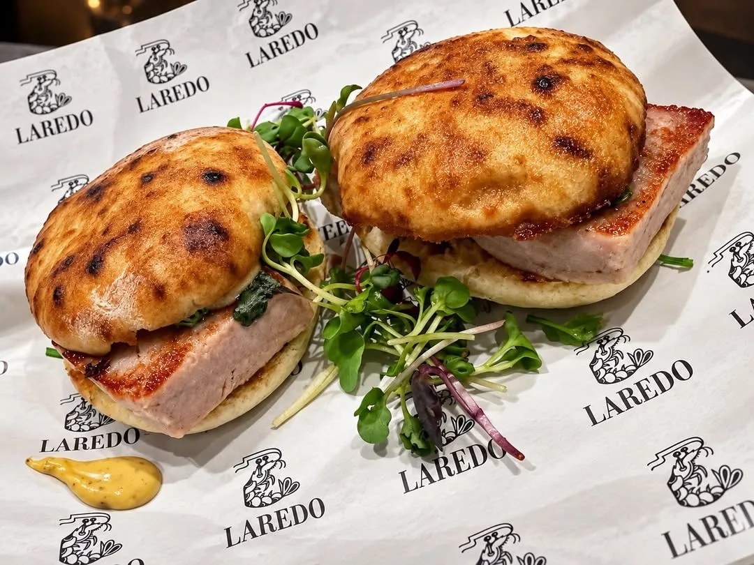 Two small toasted sandwiches on printed paper with a green salad garnish