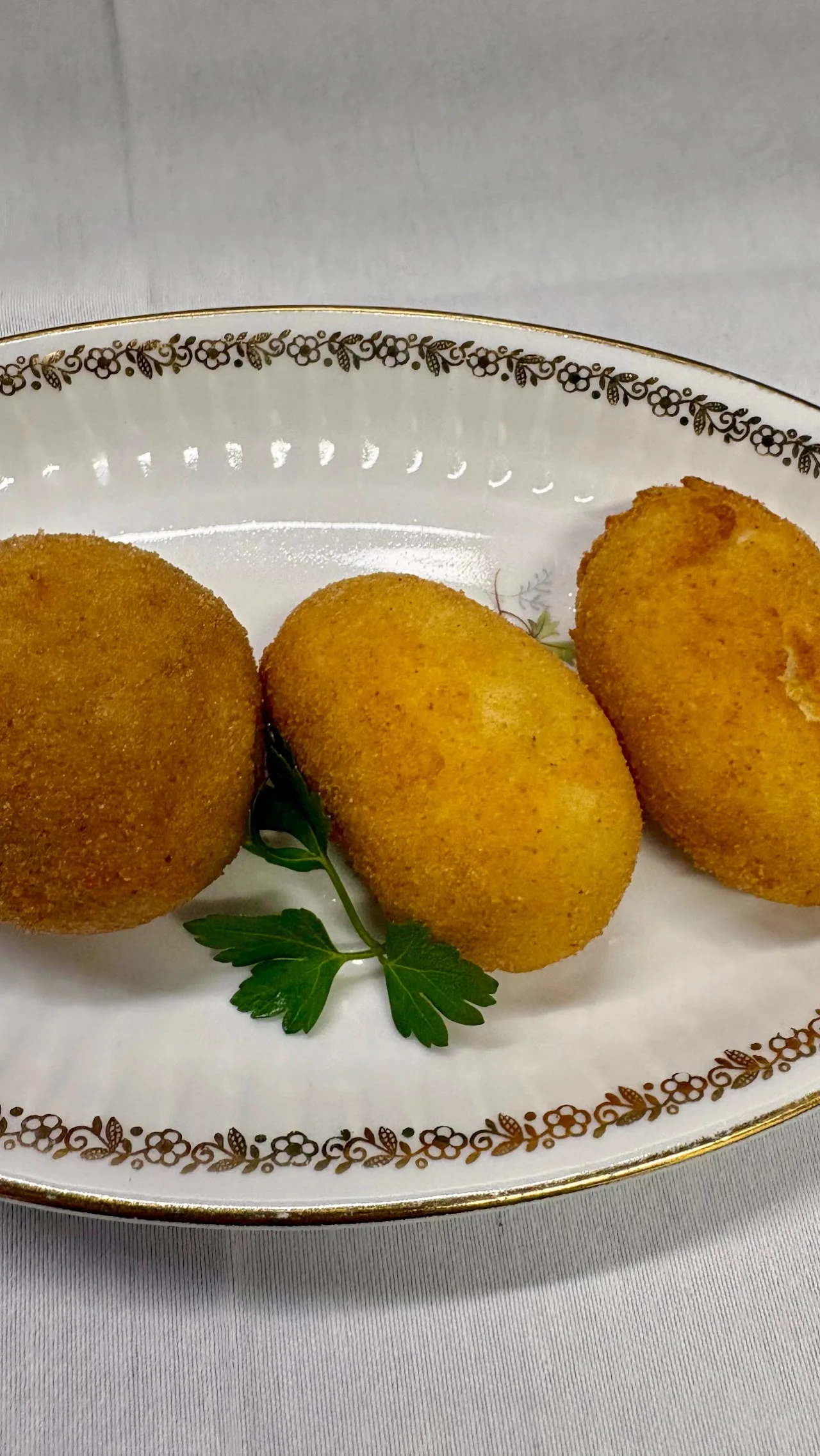 Three golden fried croquettes on a decorative plate