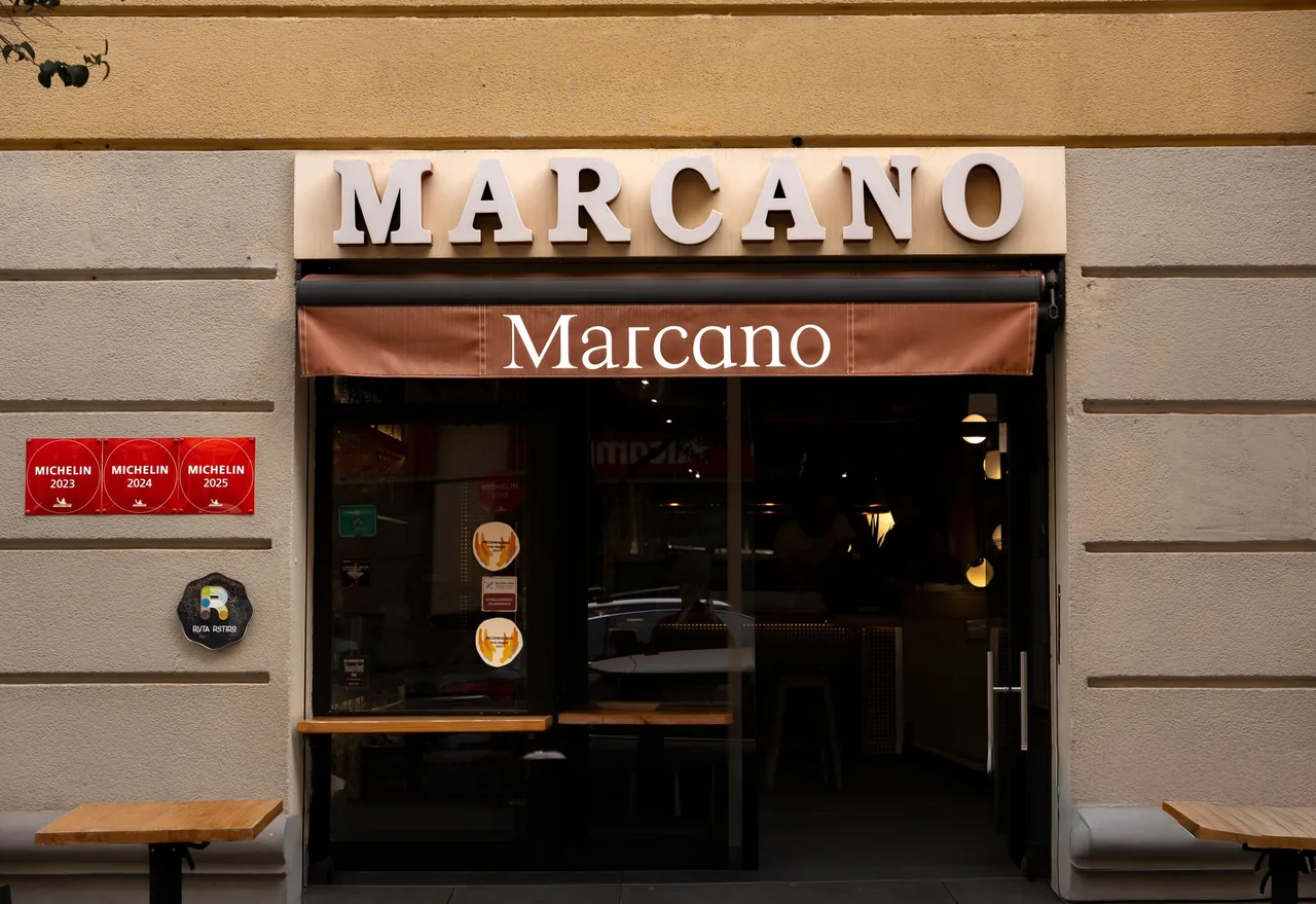 The street facade of a restaurant with a lit sign above the entrance