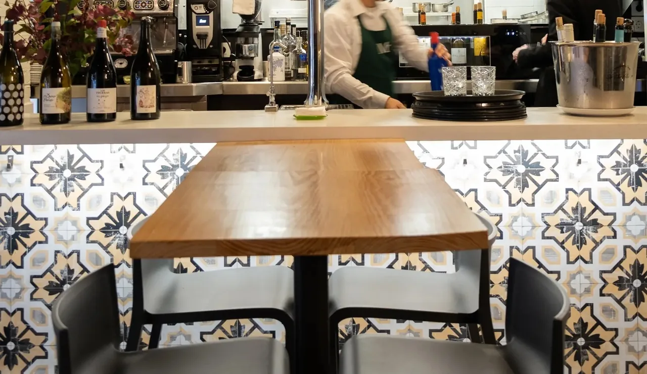 A bar counter with a wooden table and tiled floor in the foreground