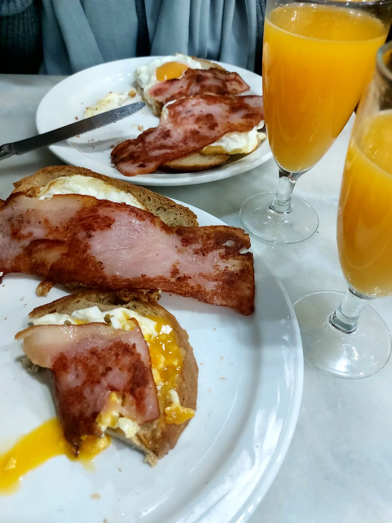 A tostada topped with cured ham and a fried egg, served with orange juice