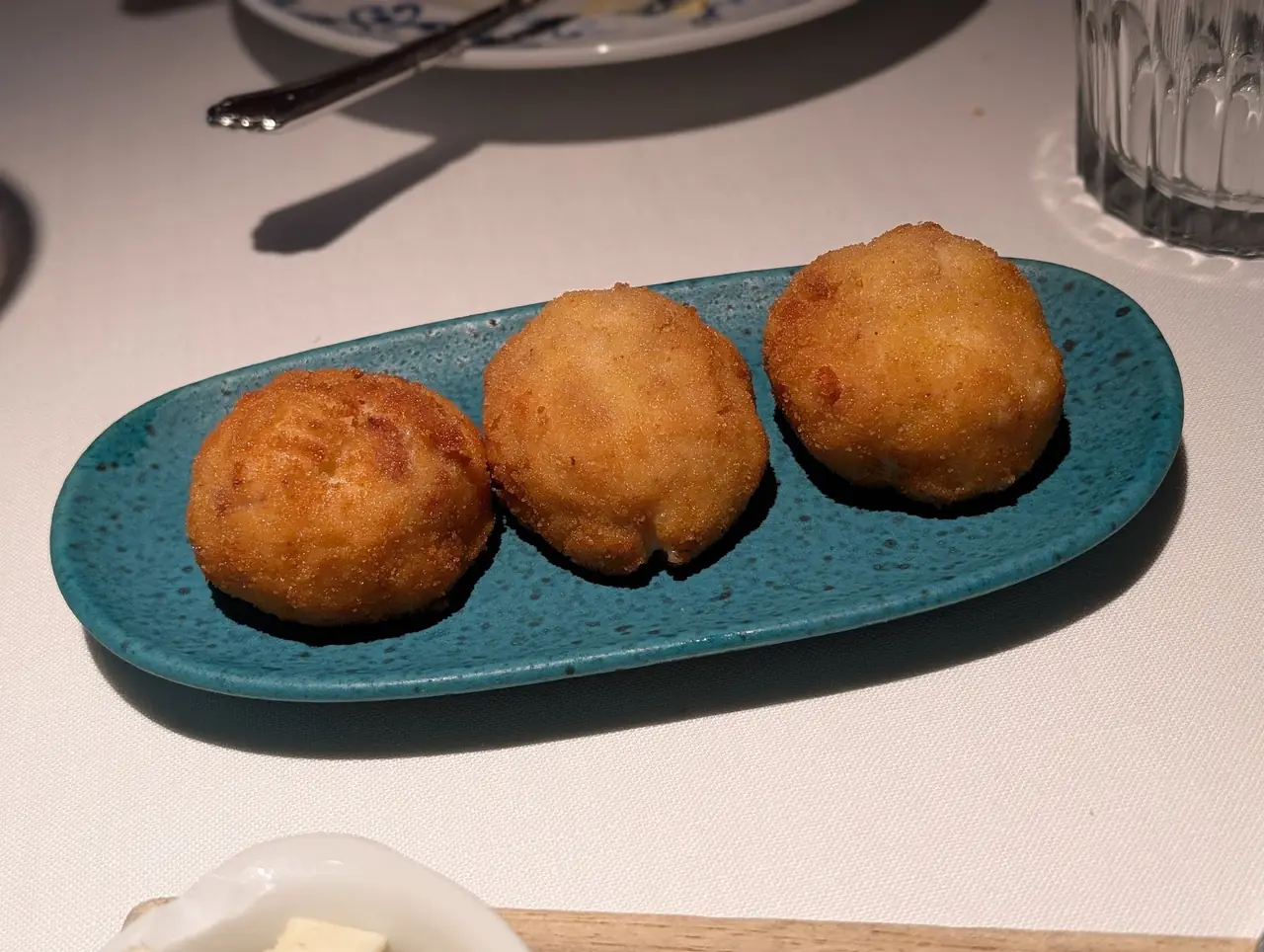 Three golden fried croquettes on a teal oval plate