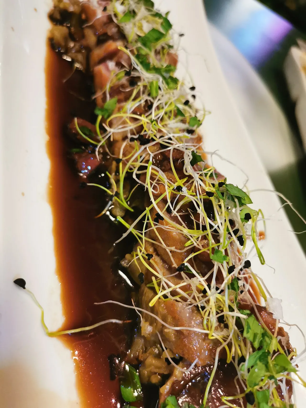 Sliced seared tuna coated in sesame seeds with a soy glaze and sprouts