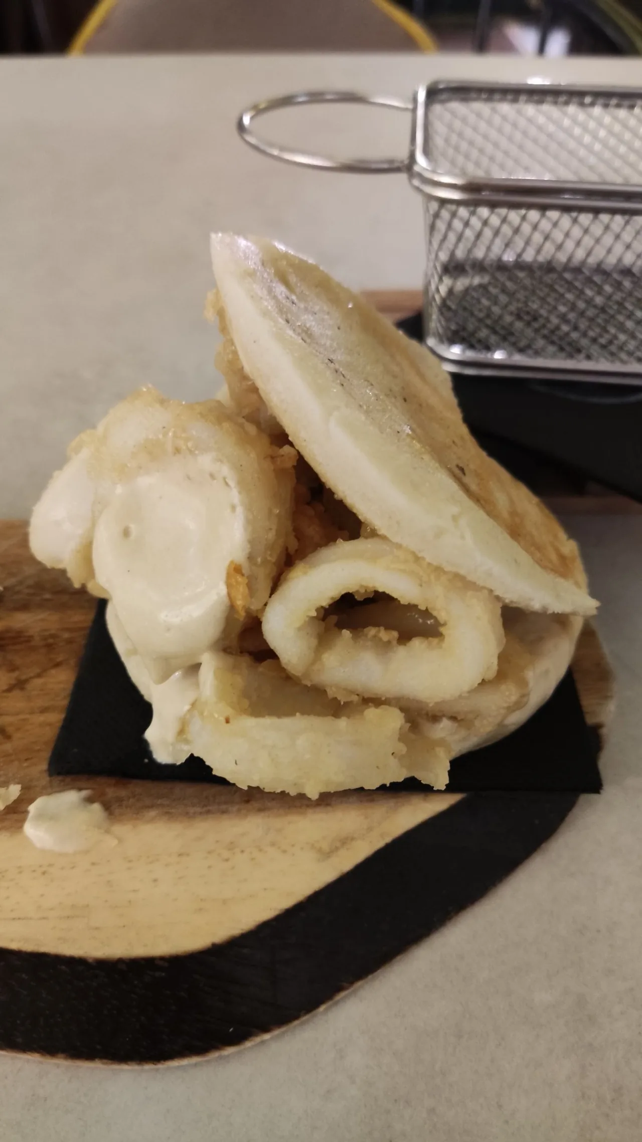 Battered fried squid in a soft white bun on a board