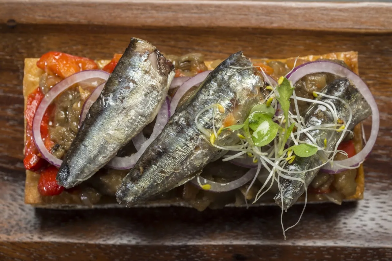 Grilled sardines over toasted bread with red pepper and onion