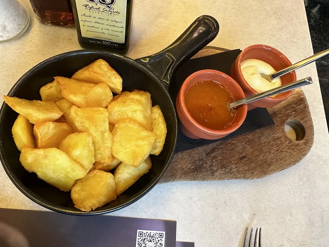 Fried potato cubes in a pan with two dipping sauces