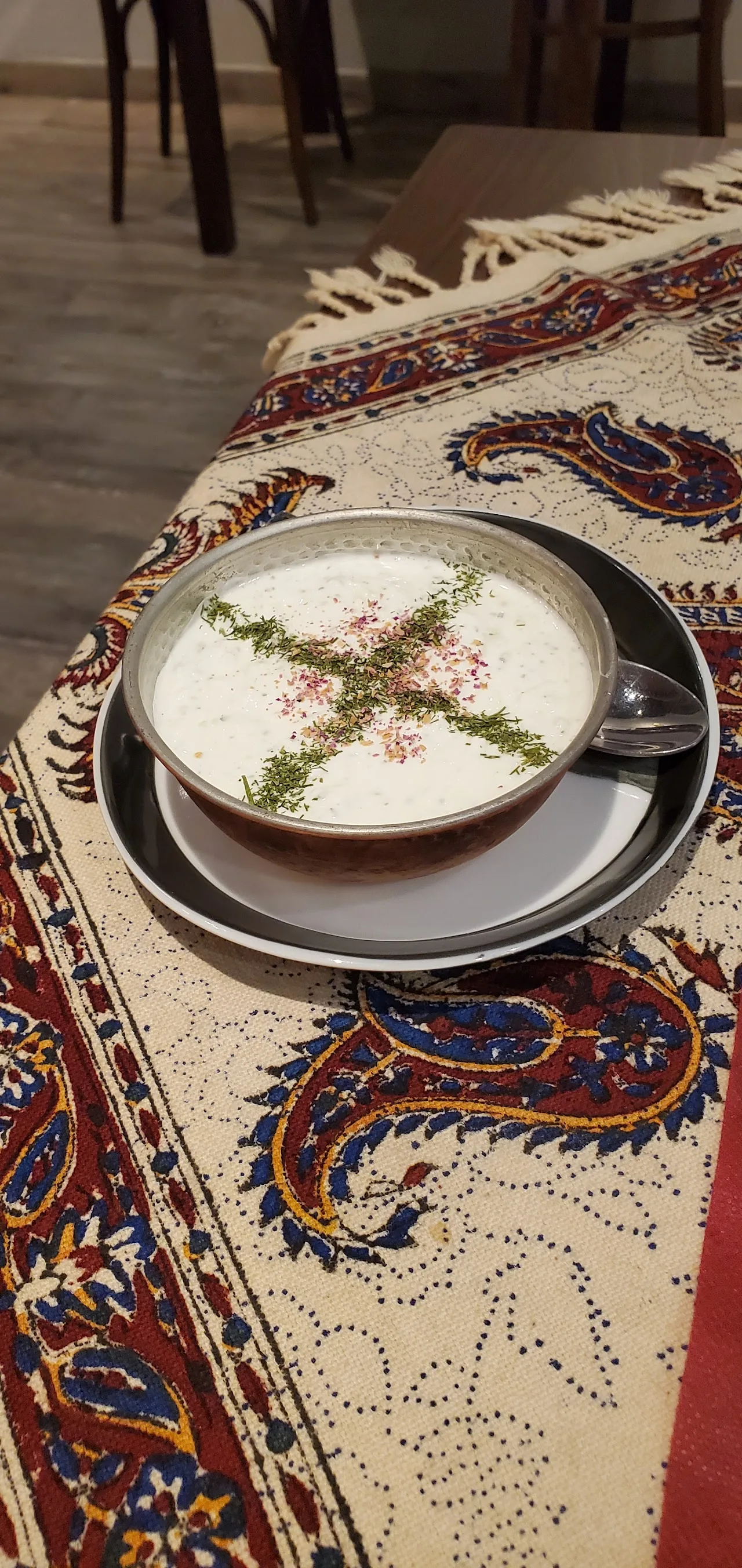 A bowl of yogurt-based soup garnished with herbs