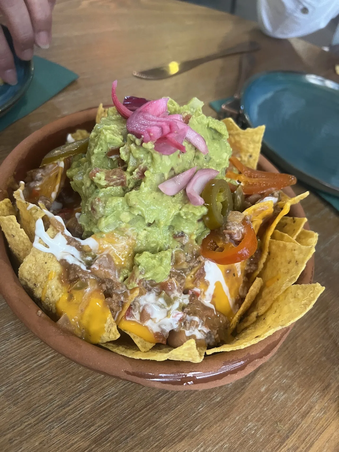 Nachos topped with guacamole and pickled onion