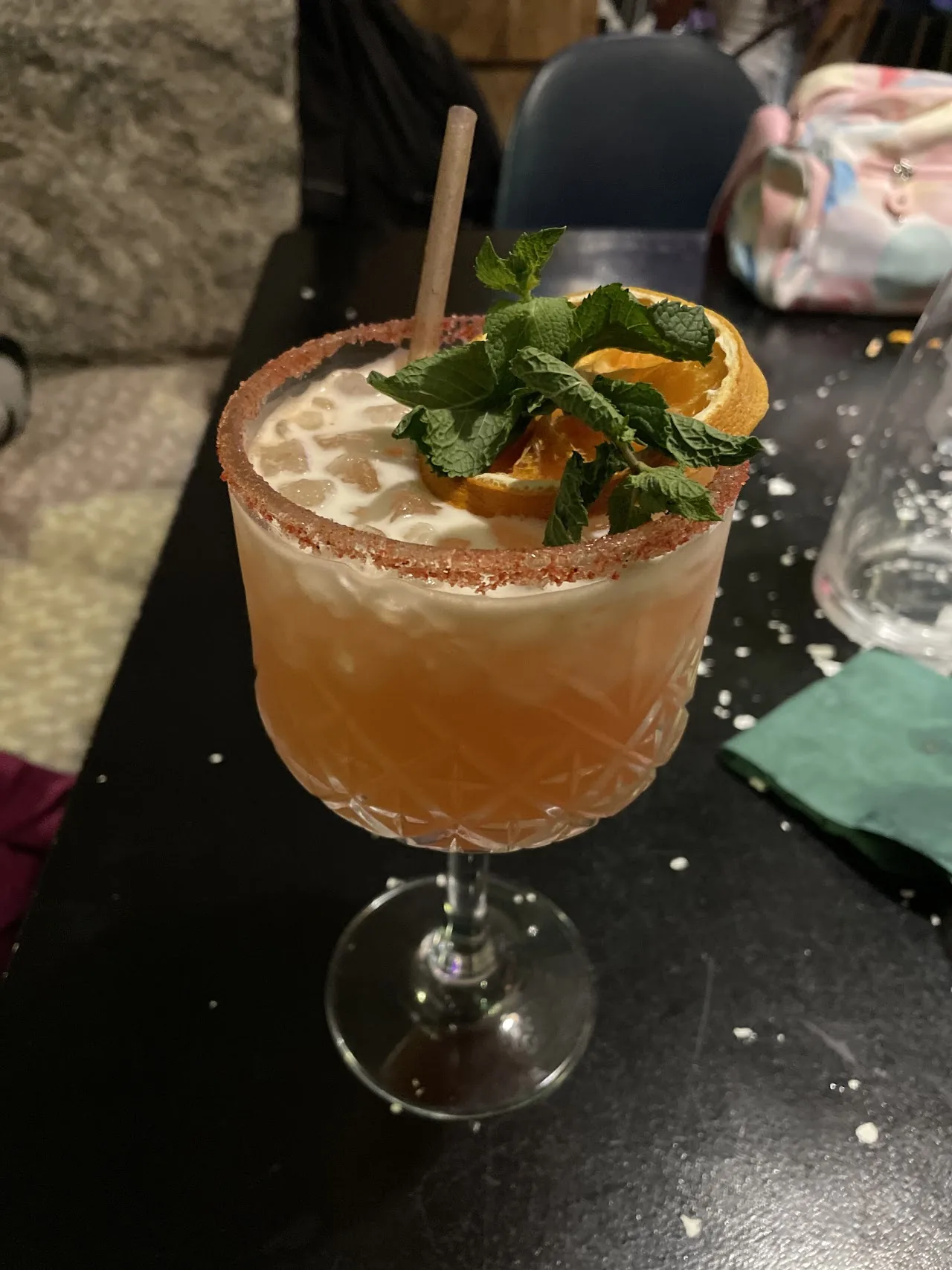 A cocktail garnished with orange and mint