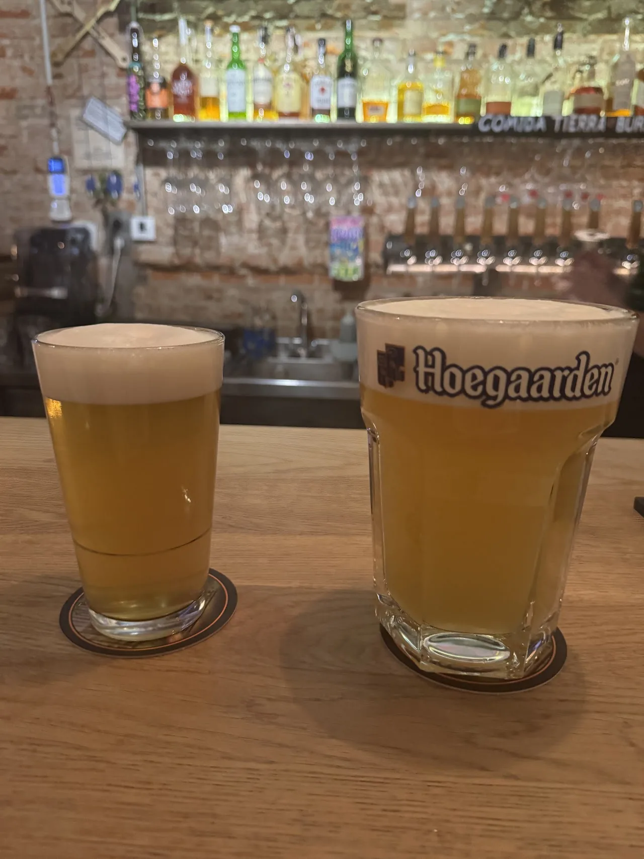 Two glasses of pale draft beer on a wooden table