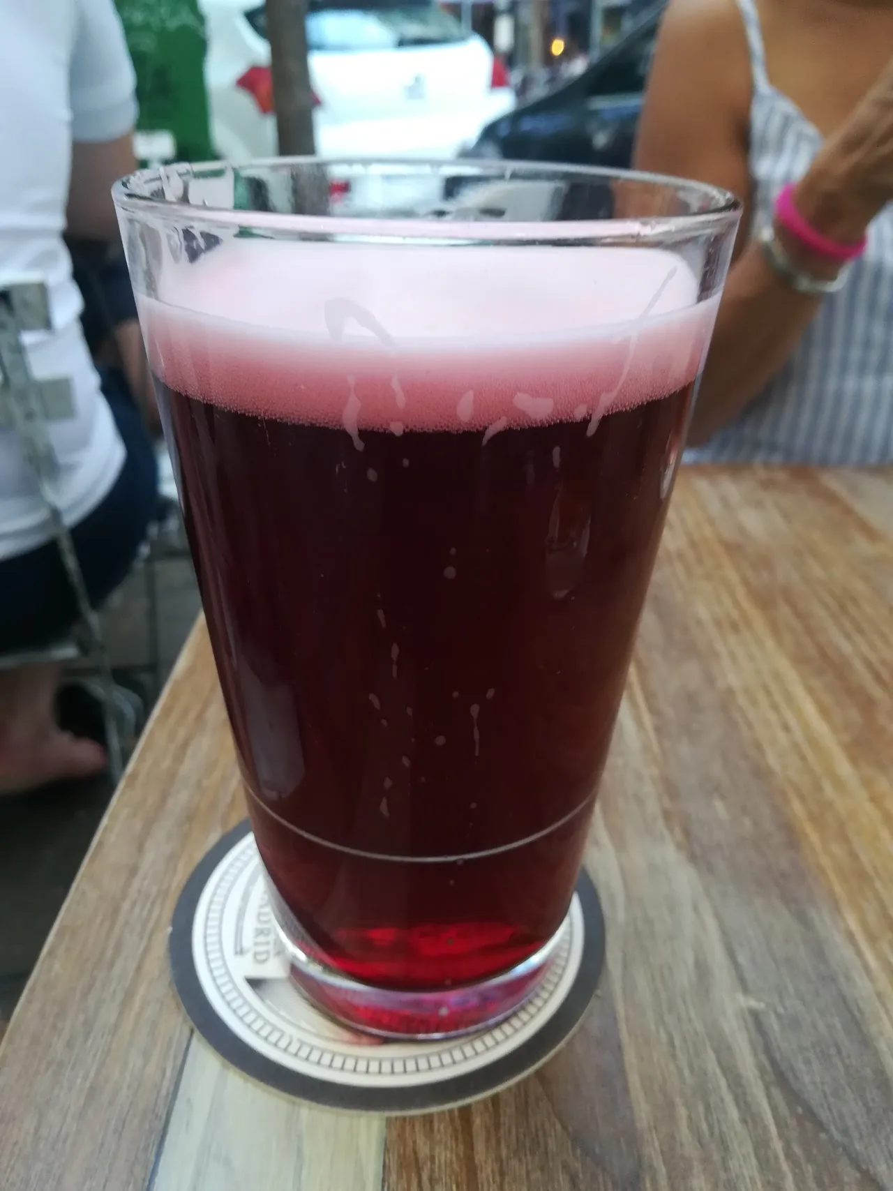 A glass of dark red beer on a wooden table