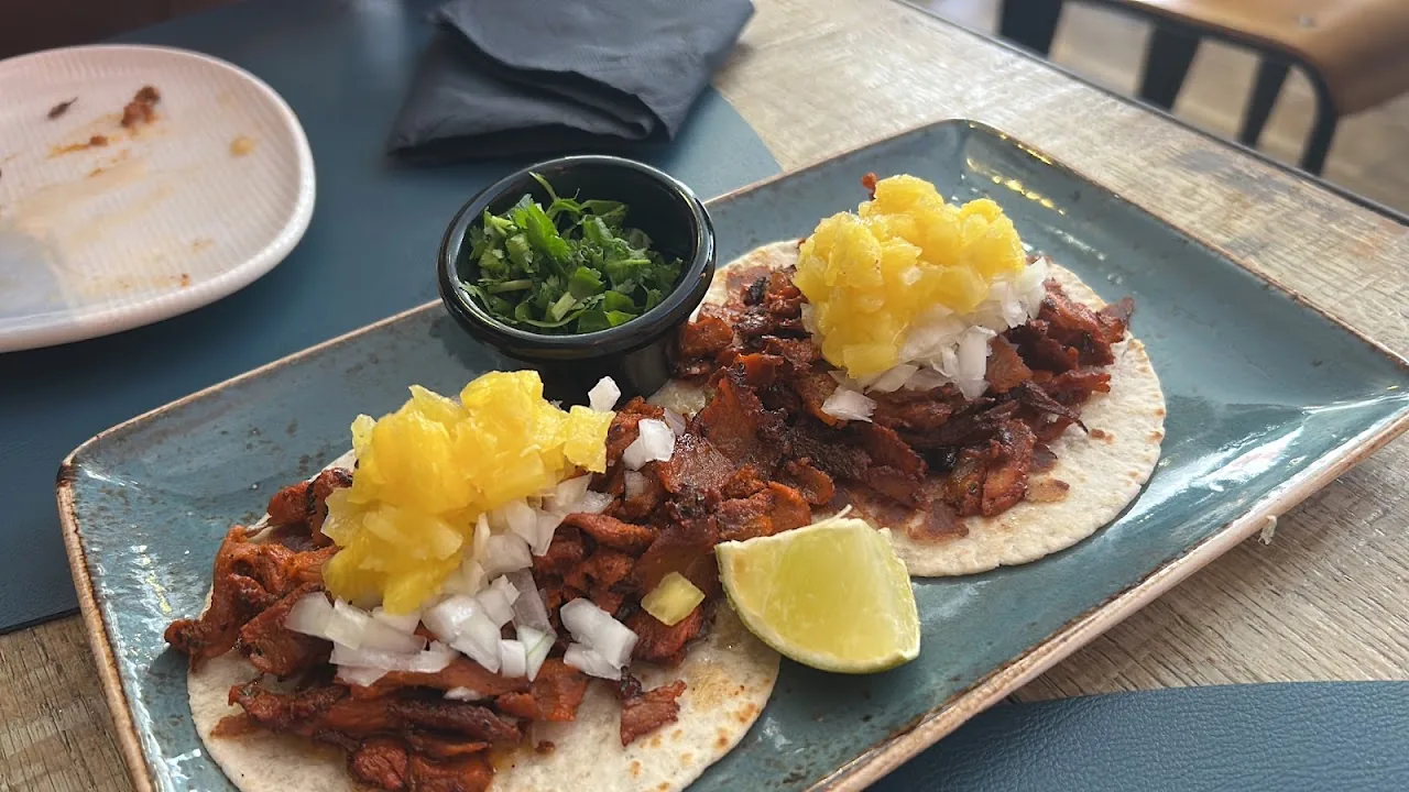 Tacos topped with pineapple, onion, and meat, al pastor style
