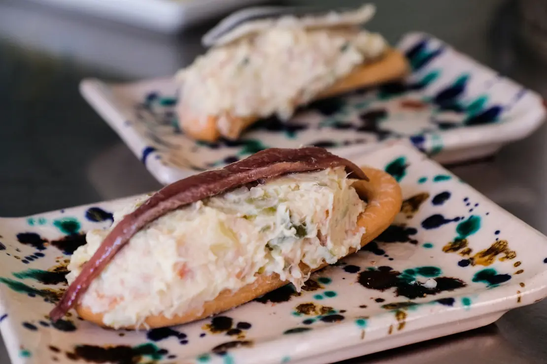 Murcian marineras: ensaladilla rusa on crisp rosquillas, one topped with an anchovy, on painted ceramic plates