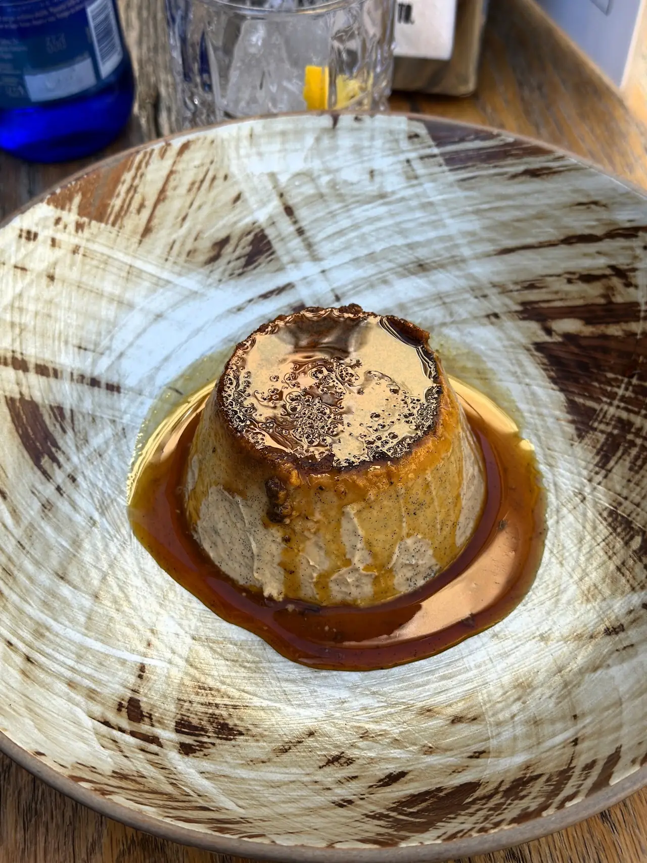 A caramel-topped flan-style dessert plated with a swirl of sauce around it.