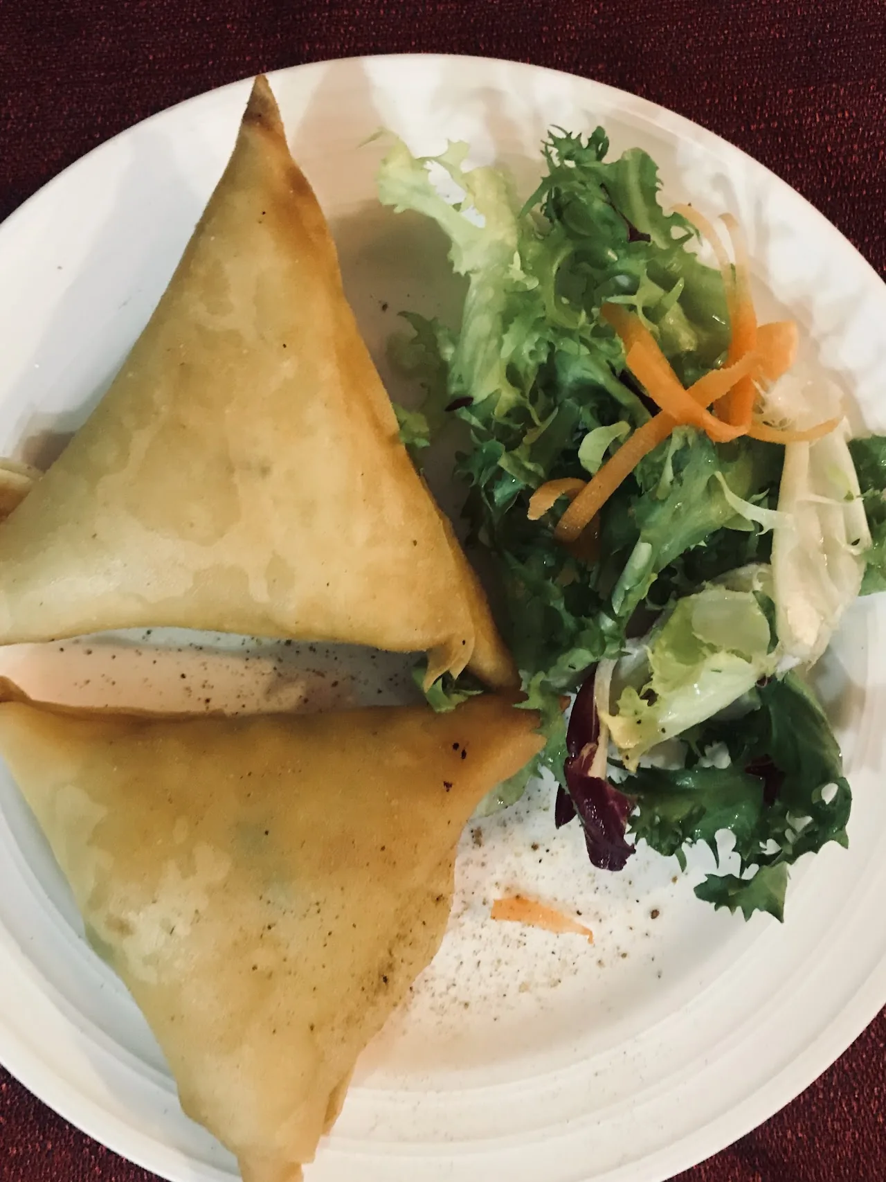 A samosa cut in half, served with a side salad