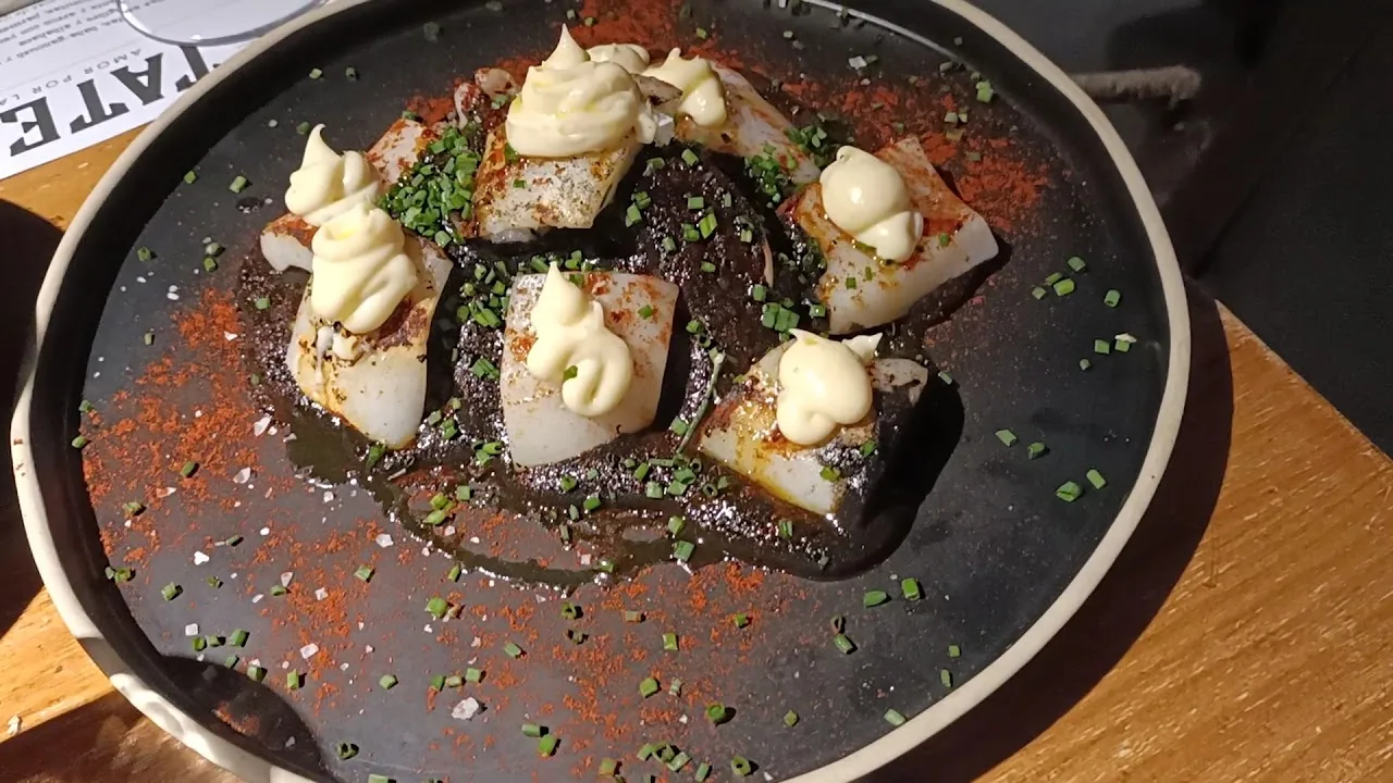 Seared scallops on a dark plate with a dollop of sauce