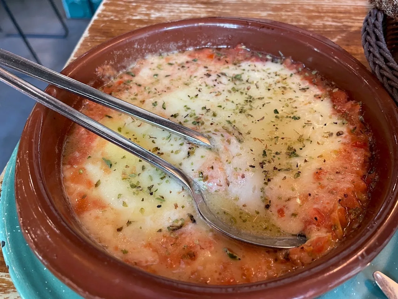 A baked cheese dish with tomato sauce in a clay pot