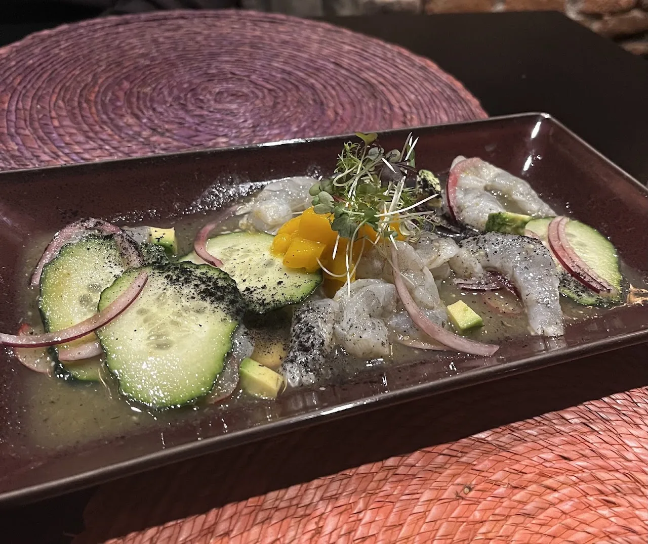 A ceviche-style dish with cucumber slices, red onion, and citrus