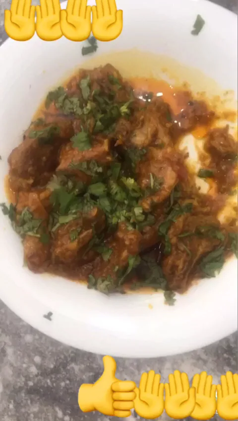 A plate of meat in sauce garnished with cilantro