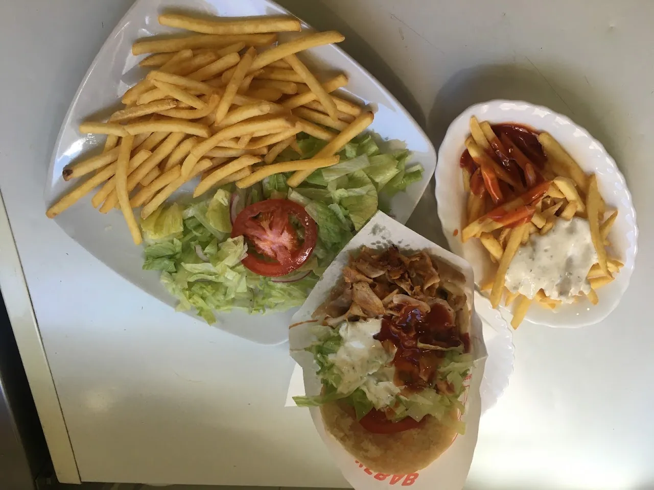 A tray of fries, salad, and wrapped sandwiches