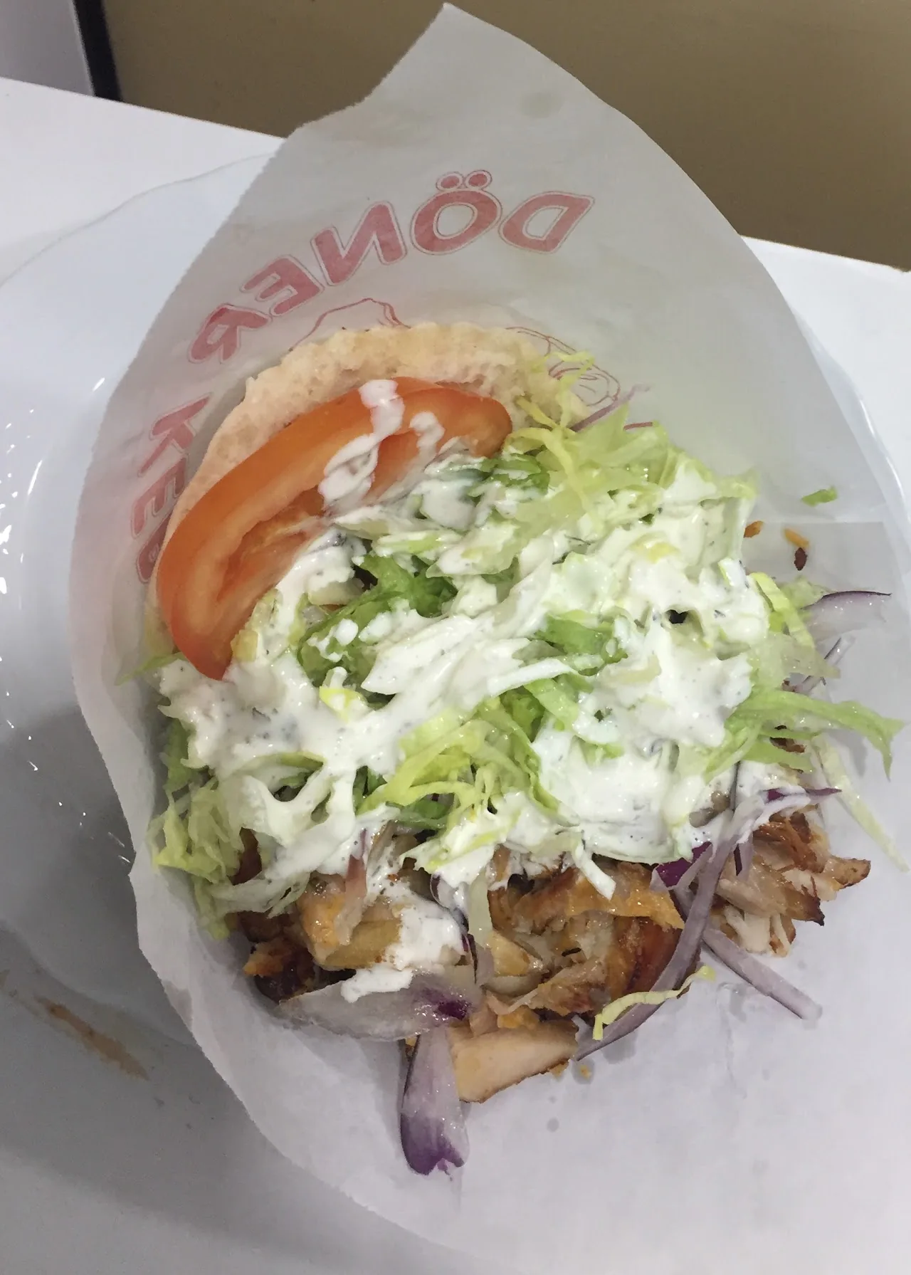 An unwrapped doner kebab wrap with shredded meat and lettuce