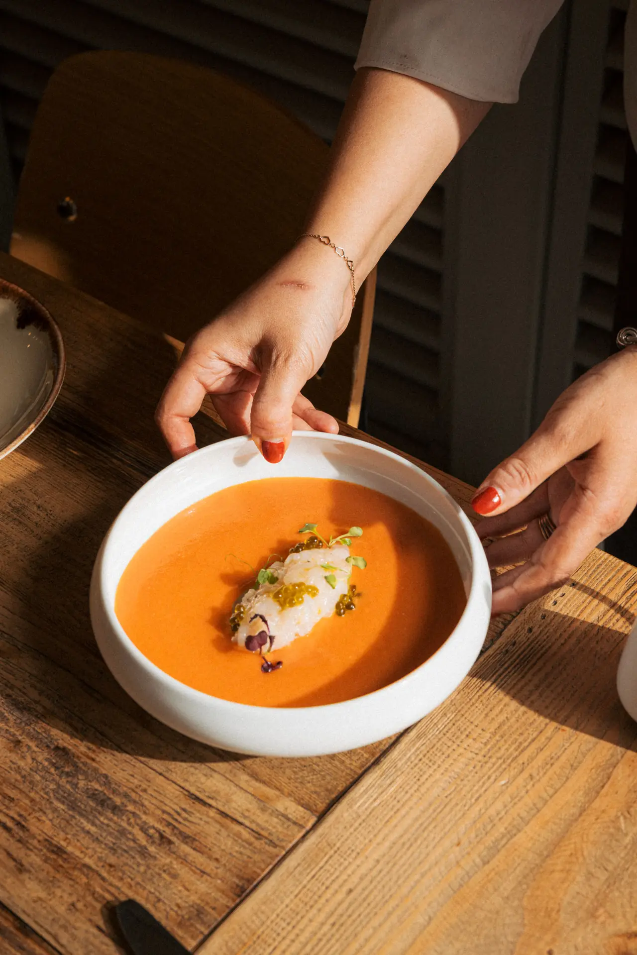 Cold tomato soup (salmorejo-style) in a white bowl topped with marinated prawn, trout roe, and microgreens, at Teleferic
