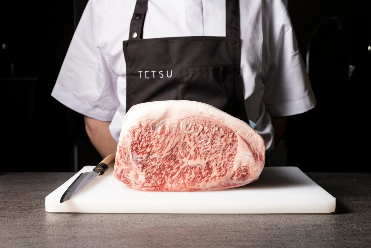 A block of marbled raw beef on a white board