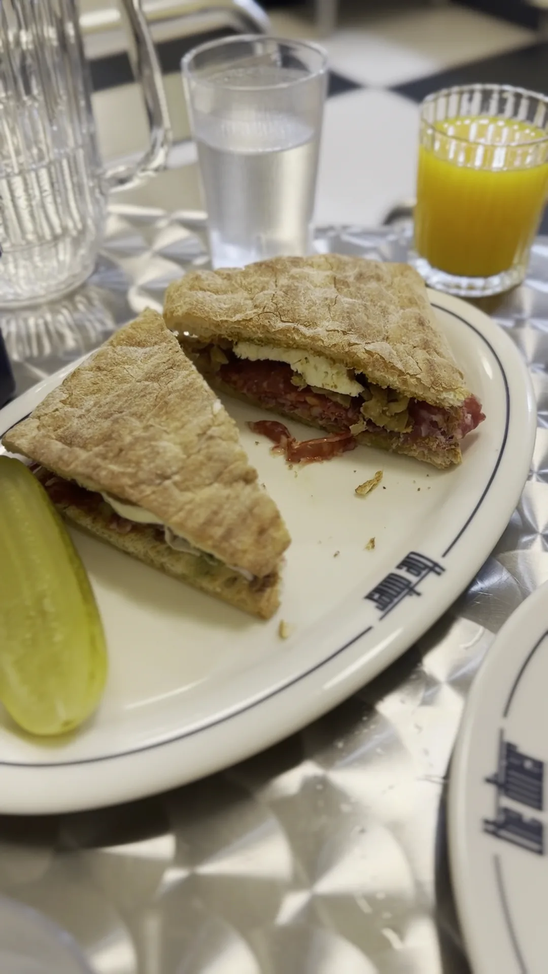 A sandwich cut in half with a pickle spear on the side