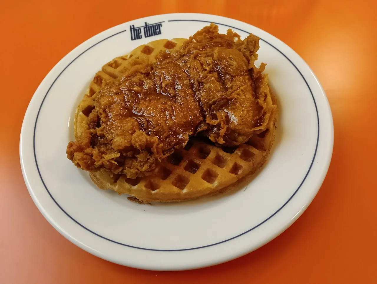 A piece of fried chicken on a waffle with syrup
