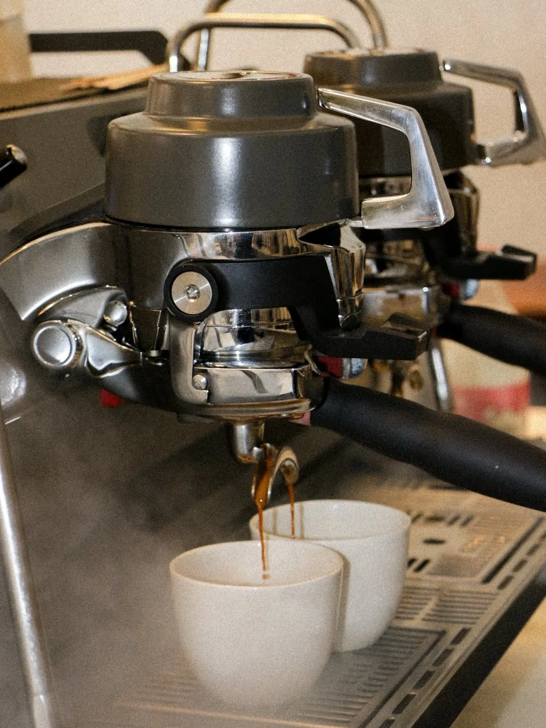 Espresso pouring from a machine into two small white cups