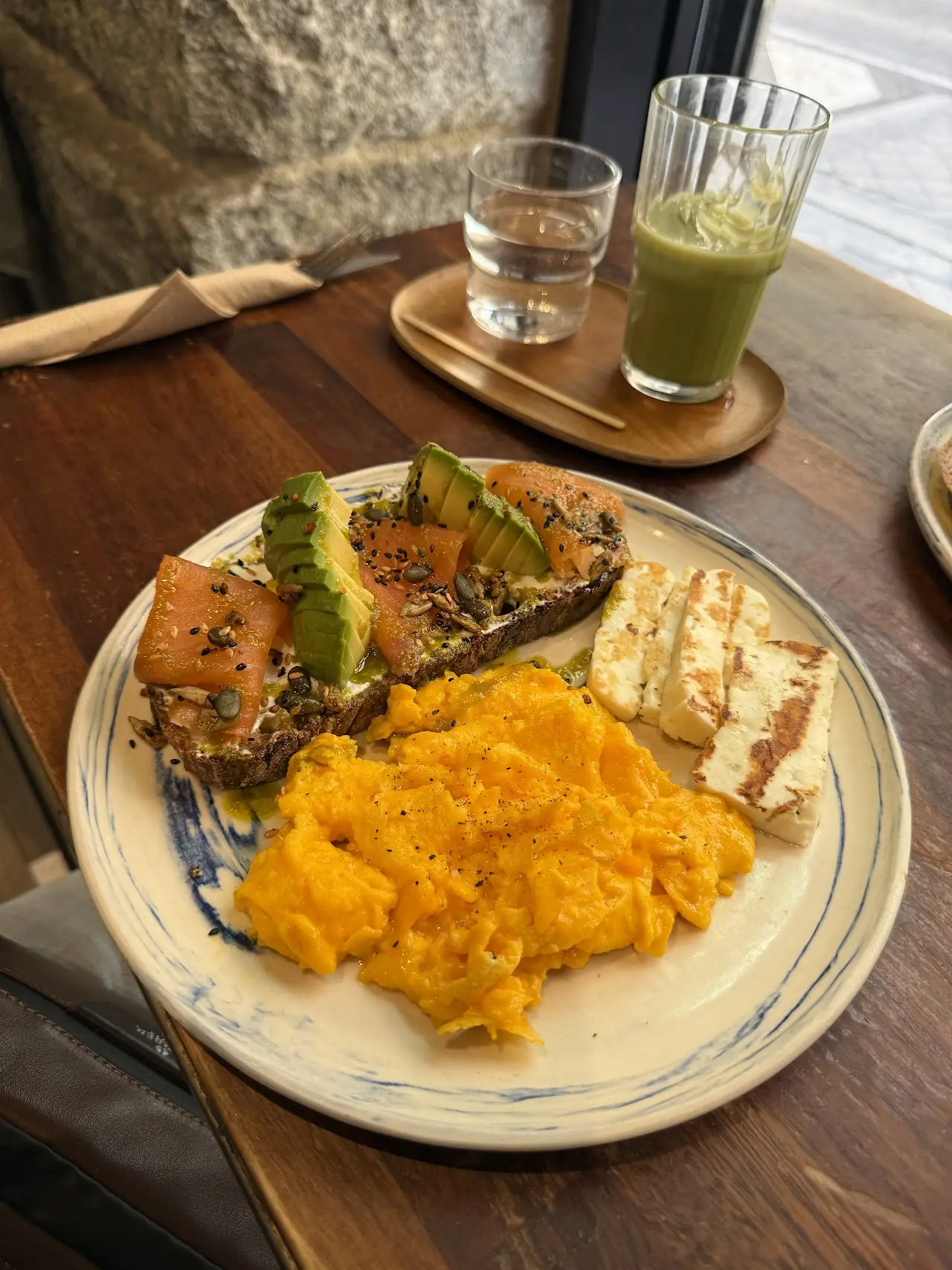 A plate of avocado toast and mashed pumpkin next to a green juice.