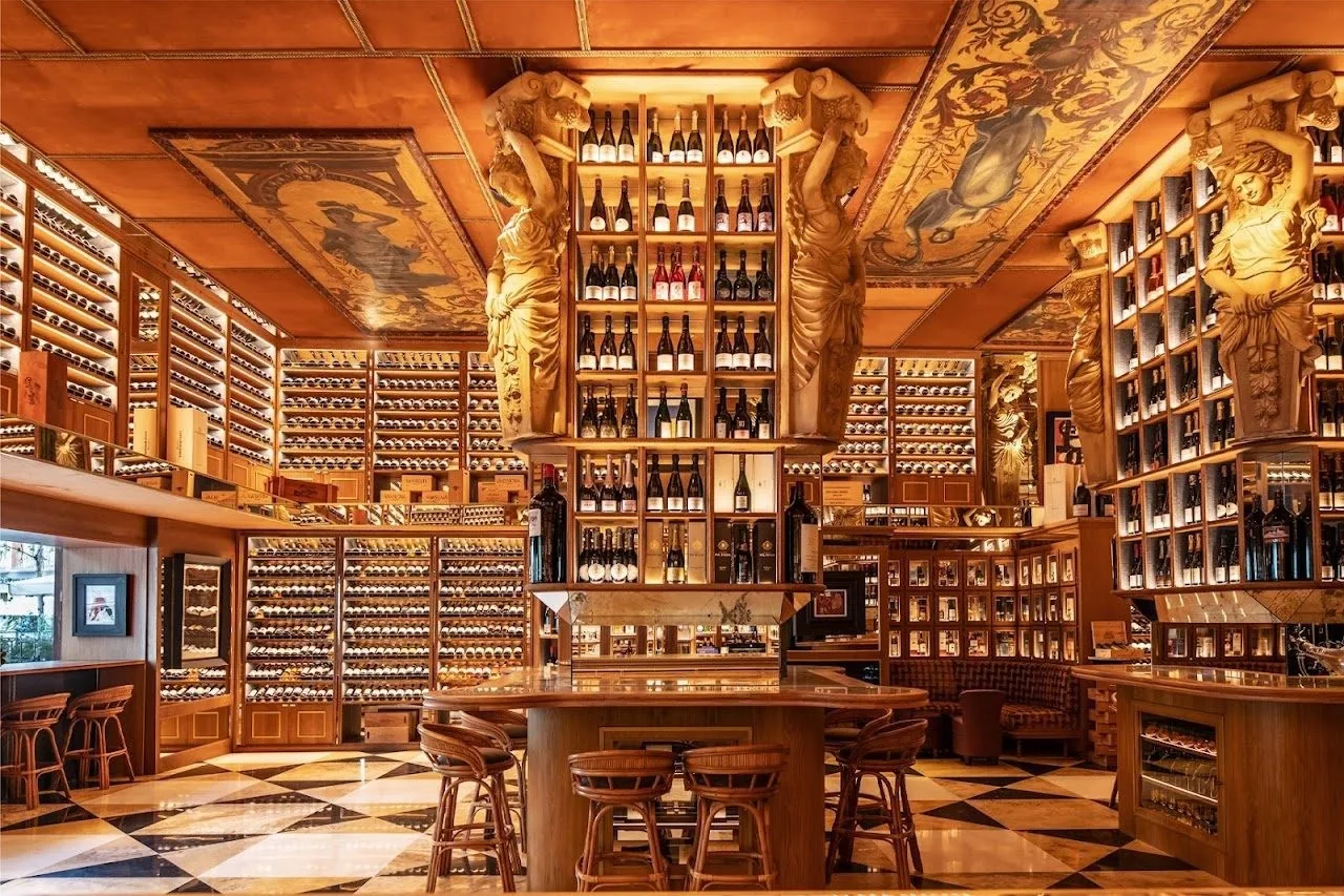 A wine room with floor-to-ceiling bottle shelves, carved statues and a central round bar