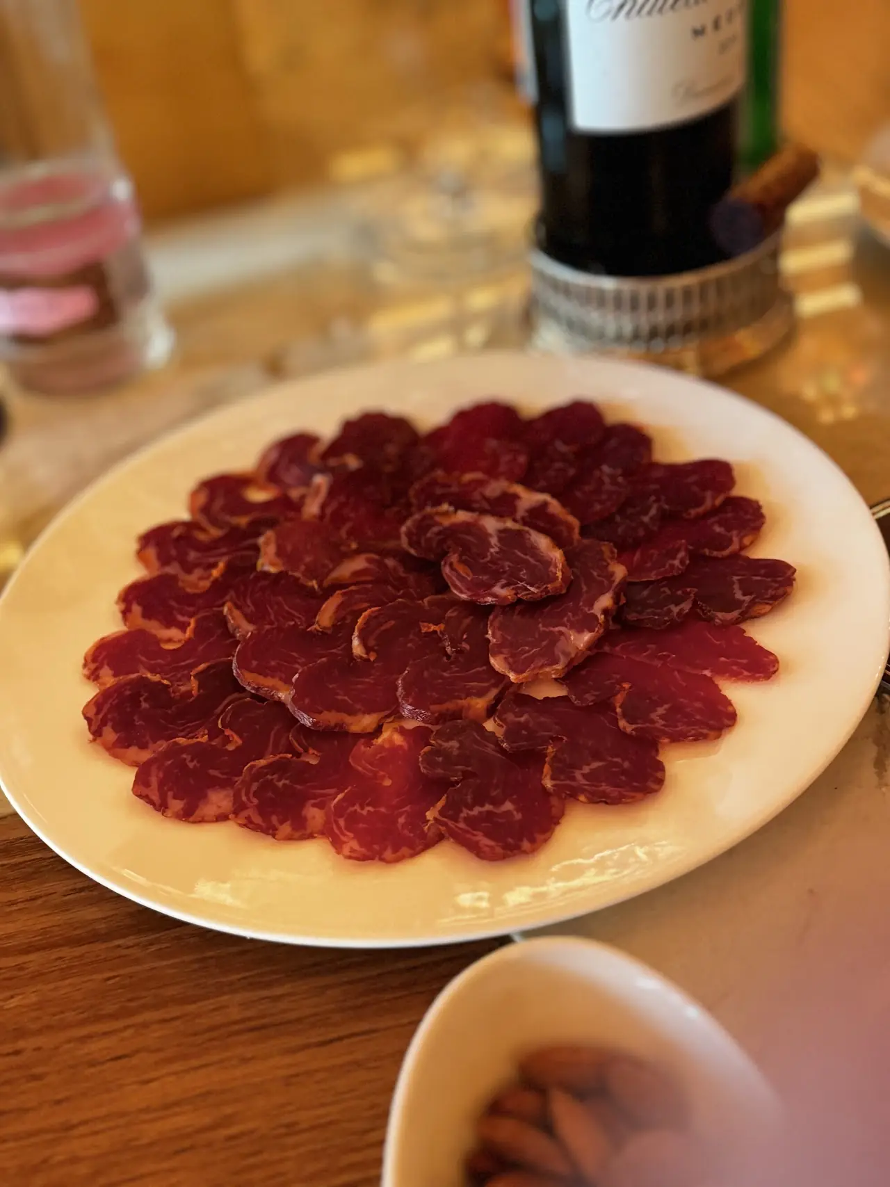 Thinly sliced cured meat arranged on a white plate.
