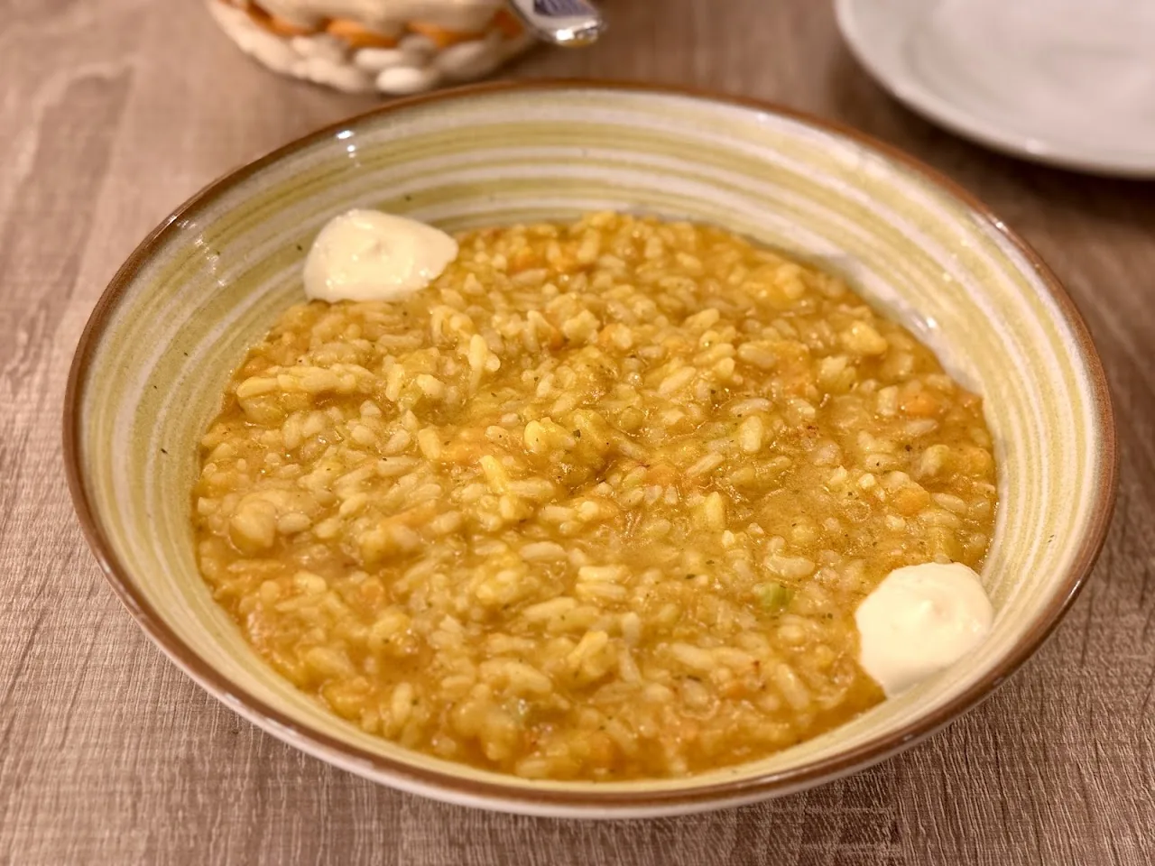 A bowl of creamy orange-hued risotto with dollops of cheese